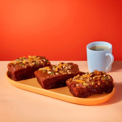 Vegan Sticky Ginger and Lemon Mini Loaf slices on yellow platter with coffee cup showing caramelised lemon topping.