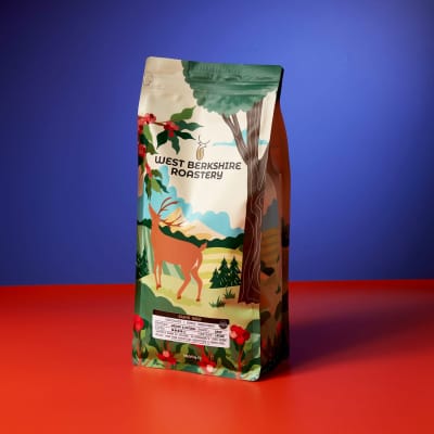 A 1kg bag of West Berkshire Roastery Black Gold coffee beans on a blue and red contrasting background