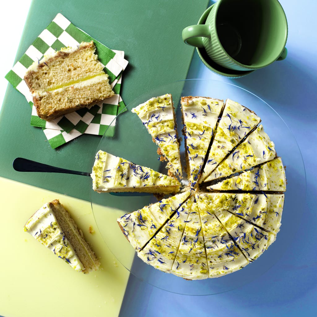 Overhead image of a round zucchini and lime cake with a blue background
